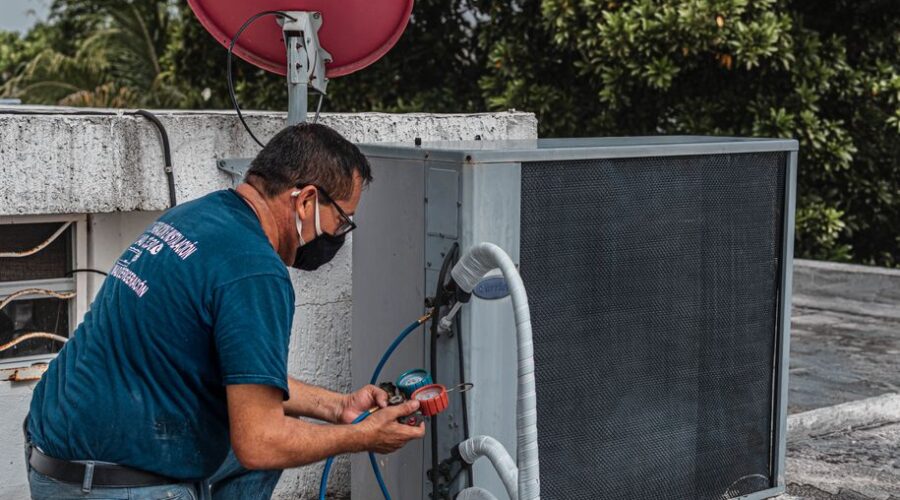 24 hour HVAC service technician repairing air conditioner at night during summer heatwave